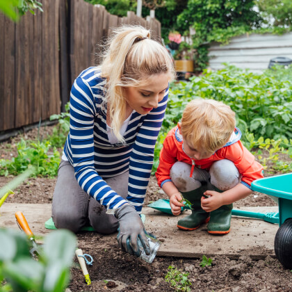 A mom and toddler digging in a garden